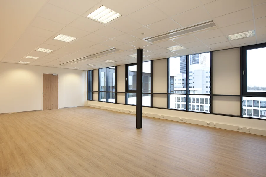 Lichte, lege kantoorruimte aan de De Boelelaan met grote ramen en uitzicht op moderne kantoorgebouwen.